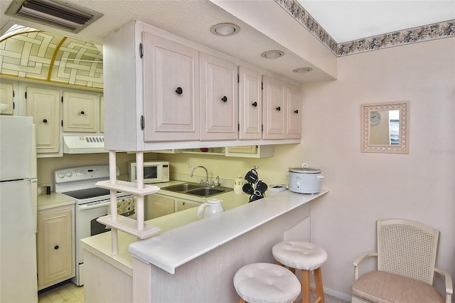 kitchen featuring premium range hood, white appliances, sink, kitchen peninsula, and a kitchen breakfast bar