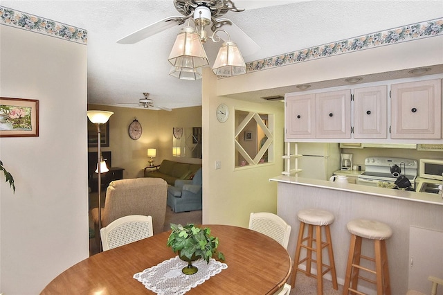 carpeted dining area featuring a textured ceiling and ceiling fan