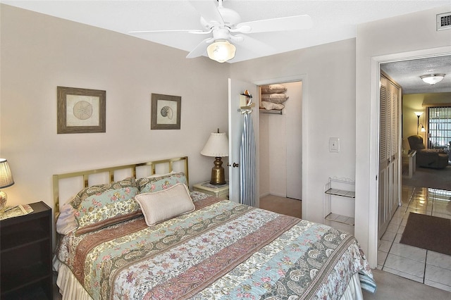 tiled bedroom with a closet, a textured ceiling, and ceiling fan