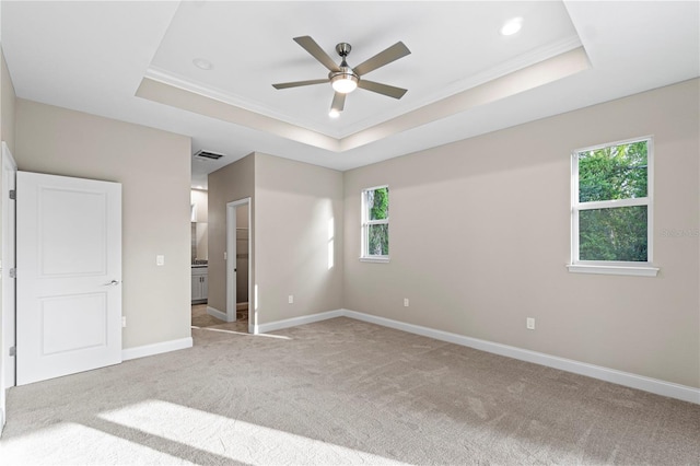 unfurnished bedroom with a raised ceiling, multiple windows, and ceiling fan