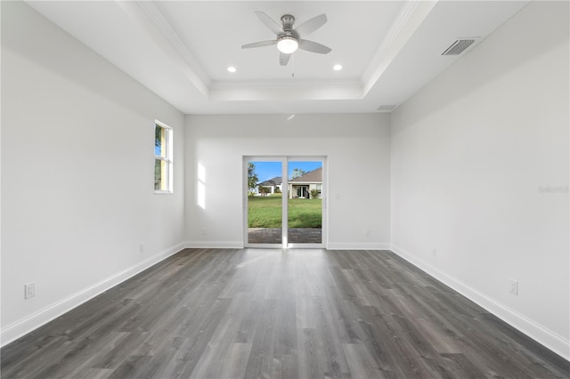 unfurnished room with dark wood-style flooring, visible vents, baseboards, ornamental molding, and a raised ceiling