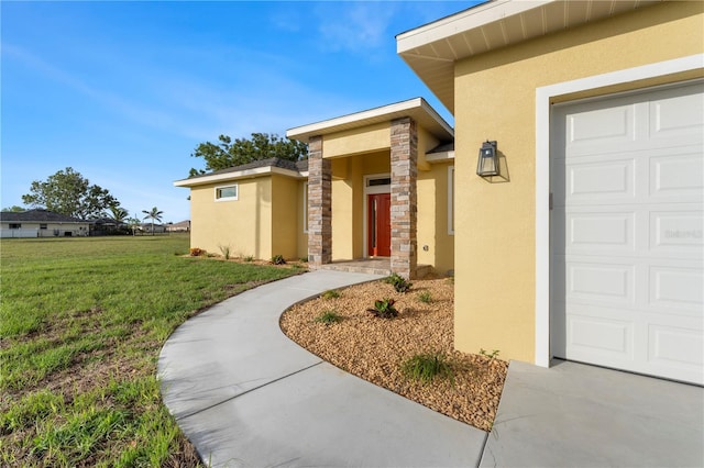 view of exterior entry featuring a garage, a lawn, and stucco siding