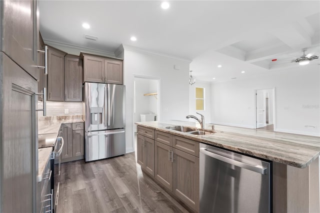 kitchen featuring light stone counters, dark wood finished floors, decorative backsplash, appliances with stainless steel finishes, and a sink