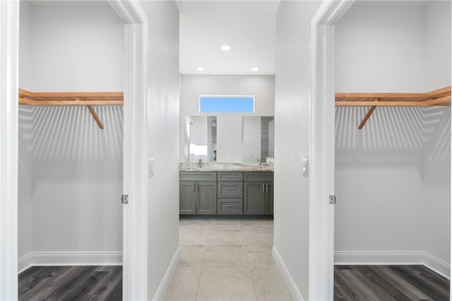 full bathroom featuring a spacious closet, double vanity, a sink, and baseboards