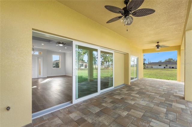 unfurnished sunroom featuring a ceiling fan and a wealth of natural light