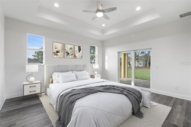 bedroom with a tray ceiling, visible vents, and access to exterior