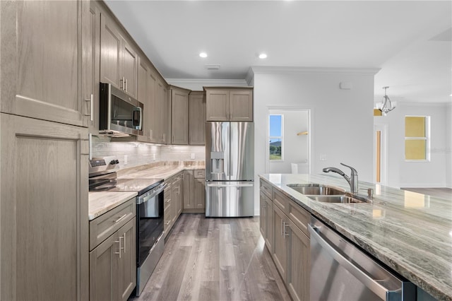 kitchen featuring light stone counters, stainless steel appliances, a sink, ornamental molding, and tasteful backsplash