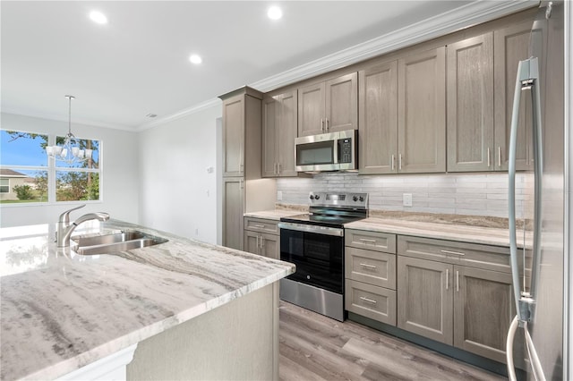 kitchen with stainless steel appliances, hanging light fixtures, backsplash, ornamental molding, and a sink