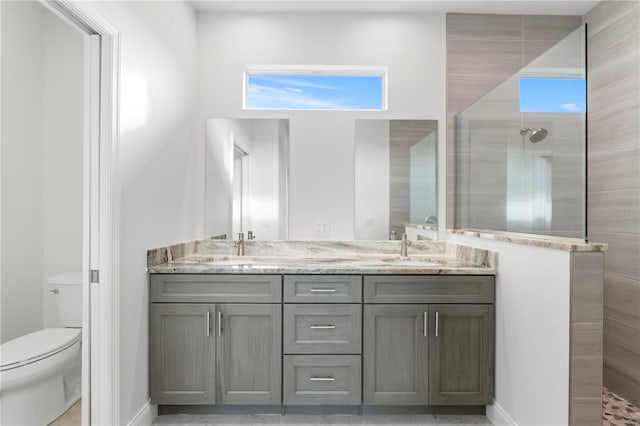 bathroom featuring double vanity, a sink, toilet, and walk in shower