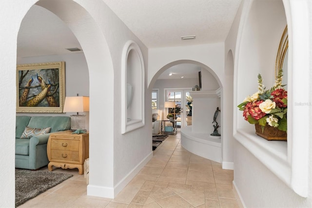 hallway with light tile patterned floors and a textured ceiling