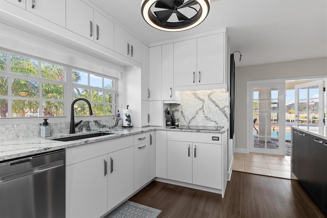 kitchen with white cabinets, dark wood-type flooring, light stone counters, stainless steel dishwasher, and sink