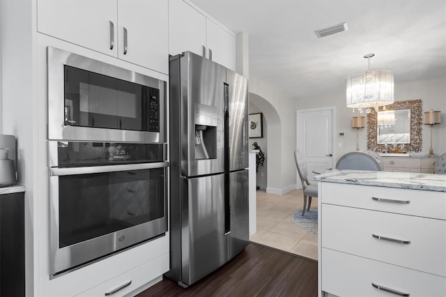 kitchen with a chandelier, dark tile patterned floors, white cabinets, light stone counters, and appliances with stainless steel finishes