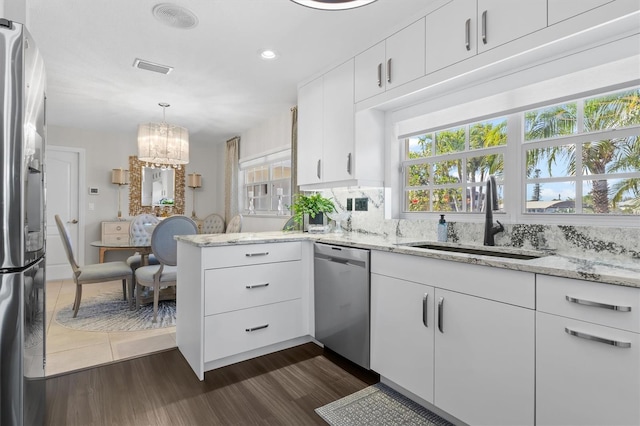 kitchen with white cabinetry, a notable chandelier, dark hardwood / wood-style floors, appliances with stainless steel finishes, and sink