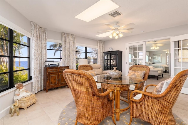 dining area with a skylight, a water view, light tile patterned floors, and ceiling fan