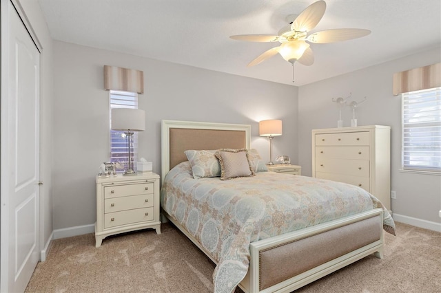 bedroom featuring light colored carpet, a closet, and ceiling fan