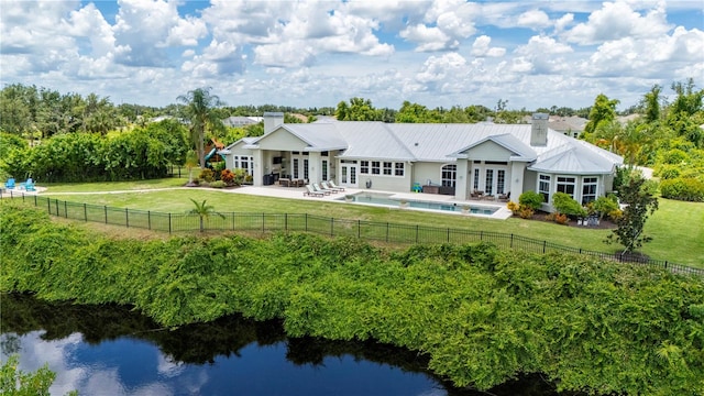 rear view of property with a patio, a water view, a fenced in pool, a yard, and french doors