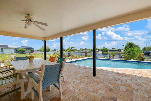 view of swimming pool featuring ceiling fan, a water view, and a patio