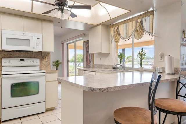 kitchen featuring white appliances, a kitchen breakfast bar, sink, kitchen peninsula, and ceiling fan