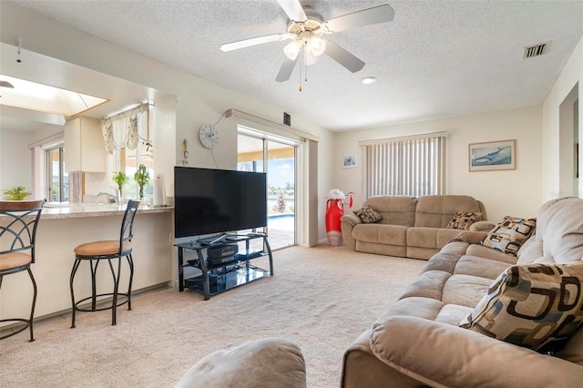 carpeted living room with a textured ceiling and ceiling fan