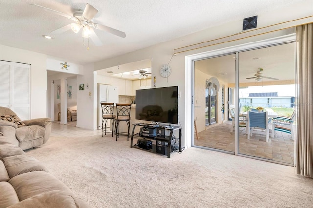 carpeted living room with ceiling fan and a textured ceiling