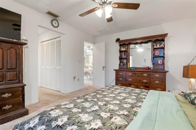 bedroom with ceiling fan, light colored carpet, and a closet