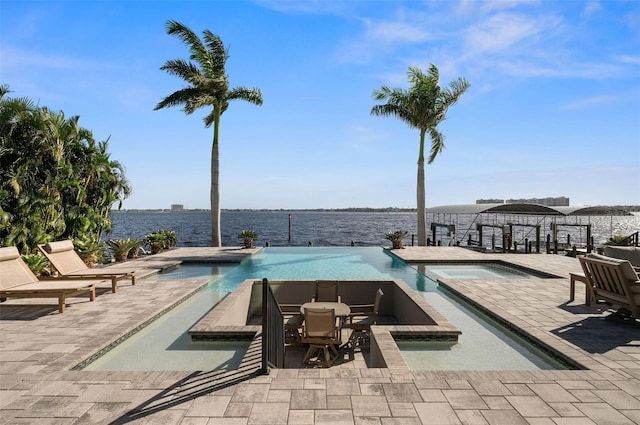 view of swimming pool with a water view, an in ground hot tub, and a patio