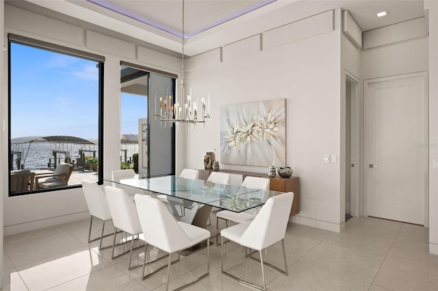 tiled dining room featuring a notable chandelier and a water view