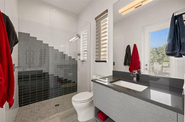 bathroom featuring toilet, vanity, tile patterned flooring, and a tile shower