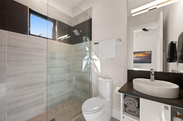 bathroom featuring toilet, vanity, and a tile shower