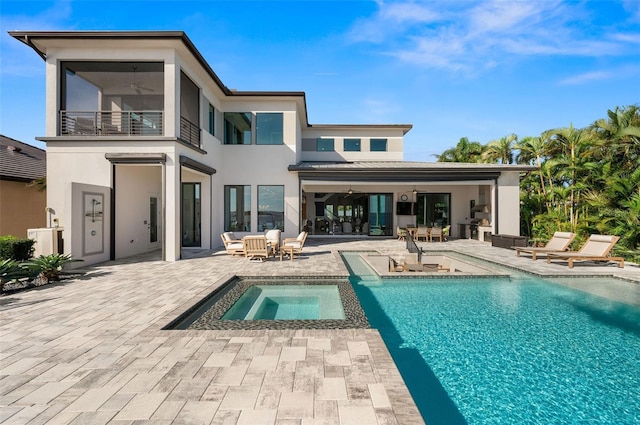 back of house featuring stucco siding, a patio, a balcony, and a pool with connected hot tub