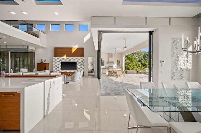 interior space featuring light tile patterned floors, a ceiling fan, open floor plan, and a towering ceiling