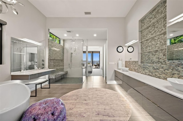 bathroom with a freestanding tub, visible vents, tiled shower, and double vanity