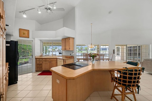 kitchen with ceiling fan, black appliances, kitchen peninsula, a high ceiling, and light tile patterned floors