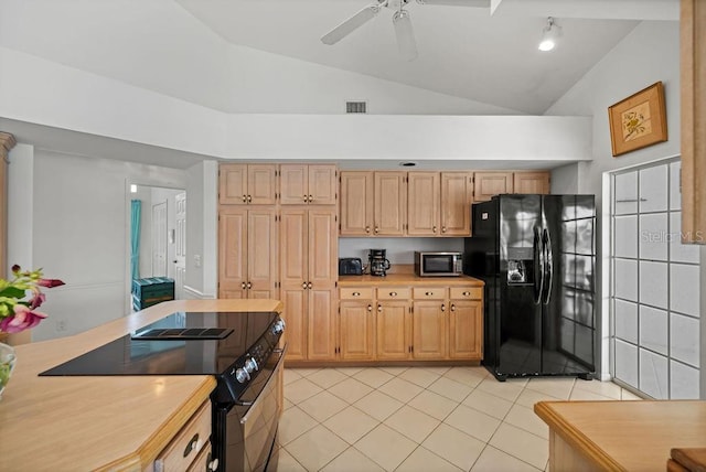 kitchen featuring light brown cabinetry, black fridge, range with electric stovetop, and light tile patterned flooring