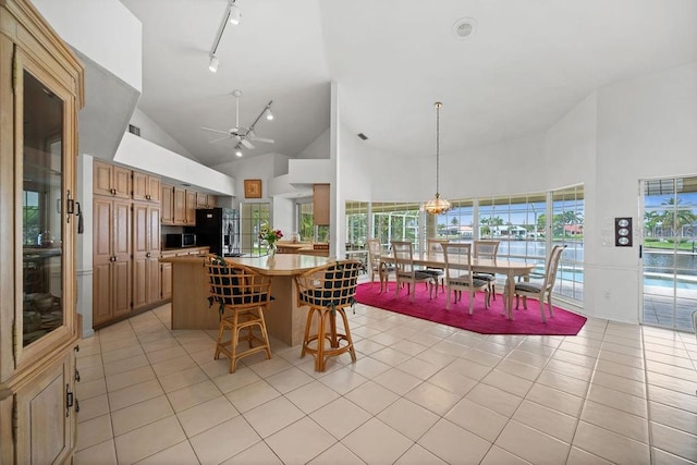 kitchen with high vaulted ceiling, light tile patterned floors, hanging light fixtures, and black fridge