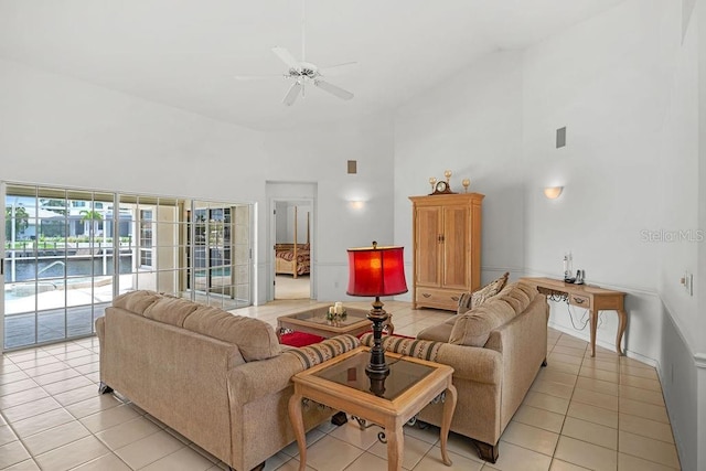 living room with ceiling fan, a towering ceiling, and light tile patterned flooring