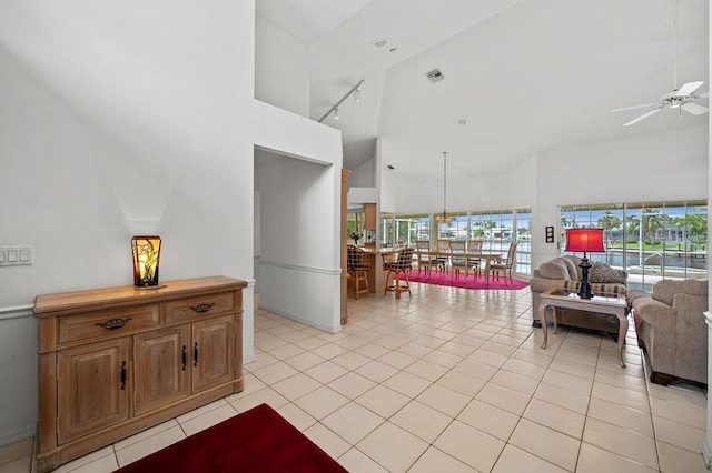 tiled living room with high vaulted ceiling, track lighting, and ceiling fan