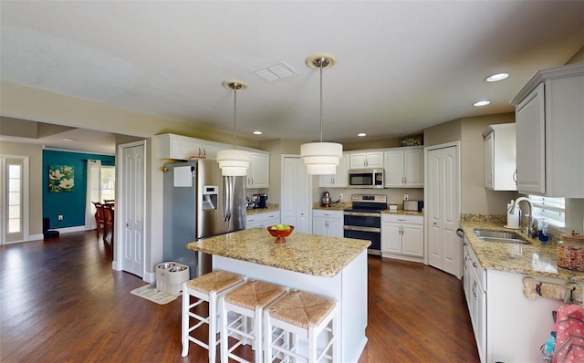 kitchen with sink, white cabinetry, a center island, hanging light fixtures, and appliances with stainless steel finishes