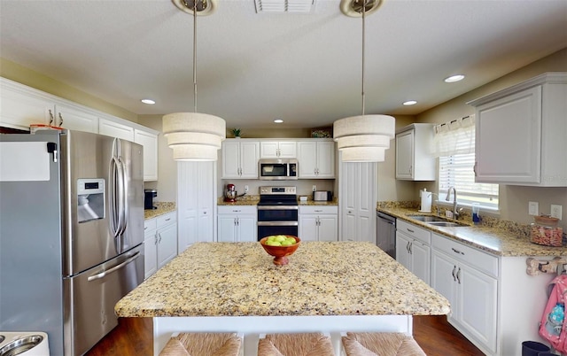 kitchen with sink, decorative light fixtures, a kitchen island, and appliances with stainless steel finishes