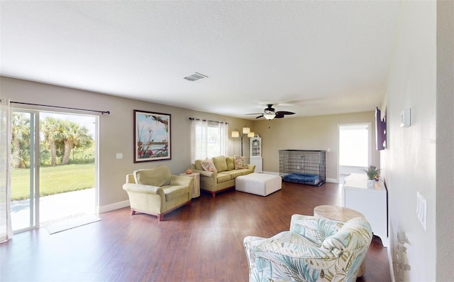 living room featuring dark wood-type flooring and ceiling fan