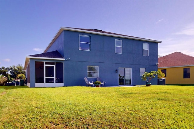 back of house featuring a sunroom and a lawn