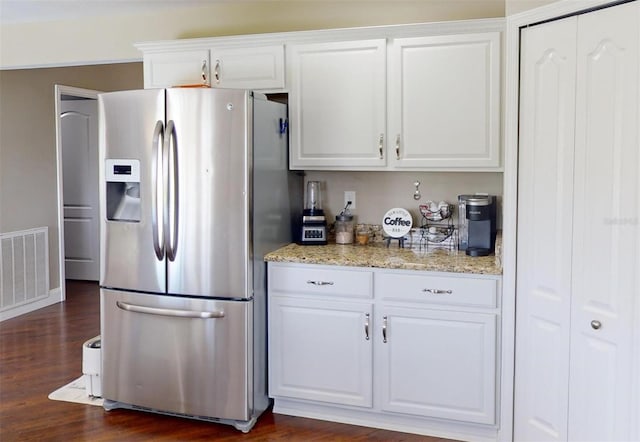 kitchen with light stone countertops, white cabinets, dark hardwood / wood-style flooring, and stainless steel fridge with ice dispenser