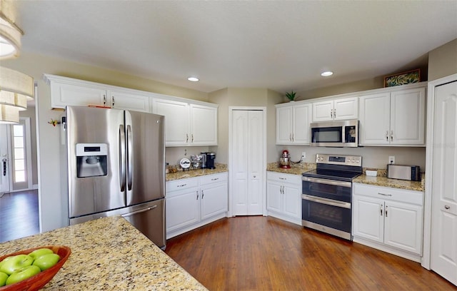 kitchen with light stone countertops, stainless steel appliances, and white cabinets