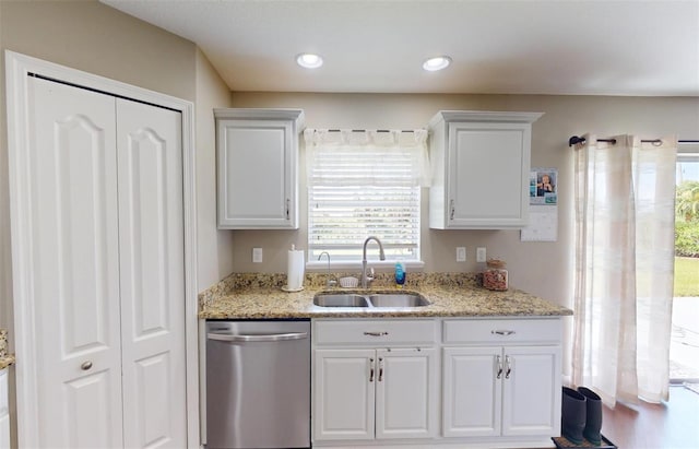 kitchen with white cabinetry, sink, stainless steel dishwasher, and light stone countertops