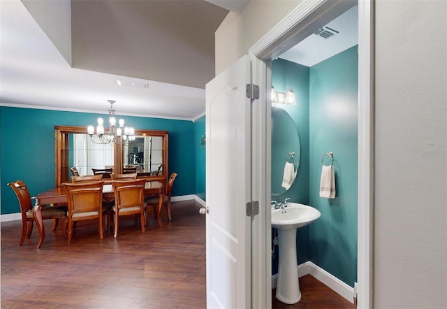 bathroom with hardwood / wood-style flooring, crown molding, sink, and a chandelier