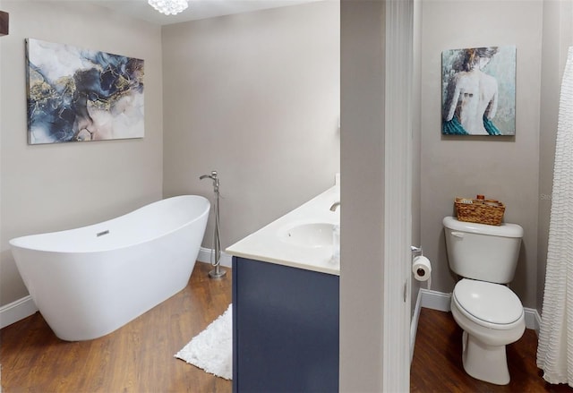 bathroom with vanity, a tub to relax in, hardwood / wood-style floors, and toilet