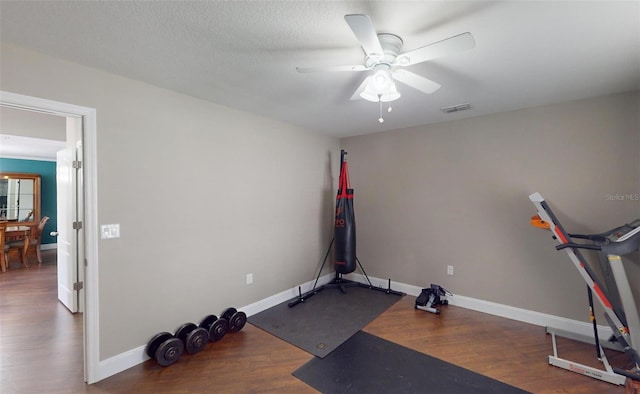 exercise area with ceiling fan, dark hardwood / wood-style flooring, and a textured ceiling