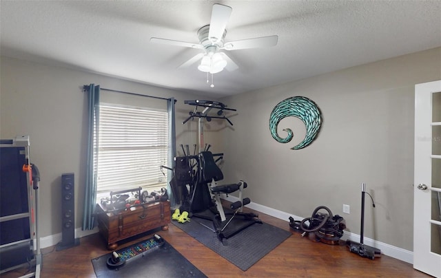 exercise room featuring ceiling fan, dark wood-type flooring, and a textured ceiling