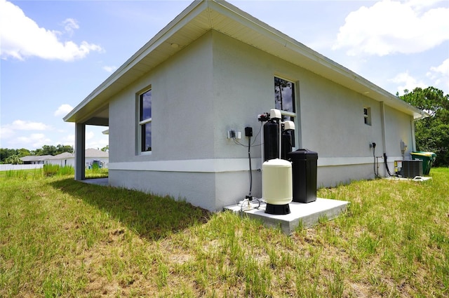 view of side of home with cooling unit and a yard