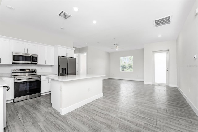 kitchen with ceiling fan, a kitchen island, white cabinets, and appliances with stainless steel finishes